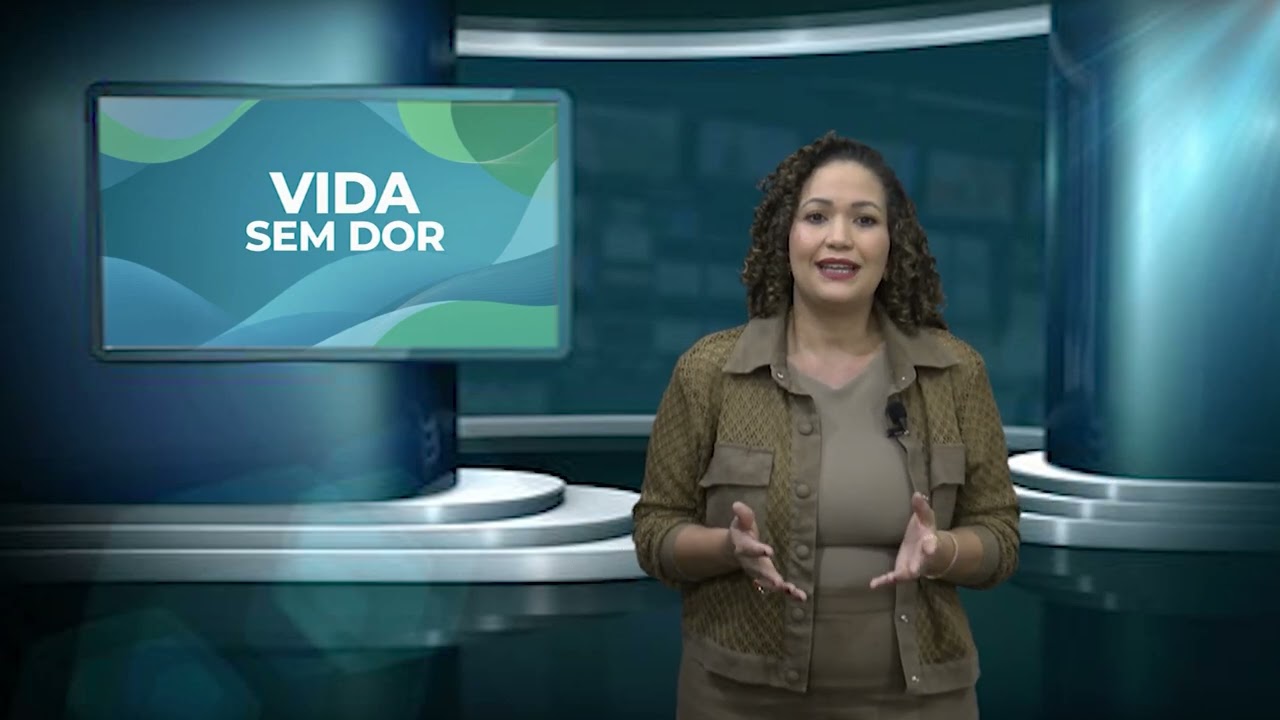 Dra. Dayane Vasconcelos no estúdio da TV Cultura de Paracatu, ao lado do painel do quadro Vida Sem Dor