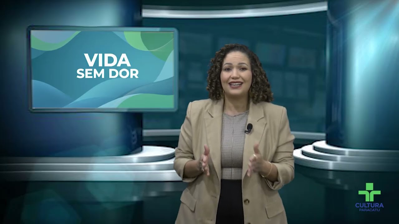 Dra. Dayane Vasconcelos no estúdio da TV Cultura de Paracatu, ao lado do painel do quadro Vida Sem Dor